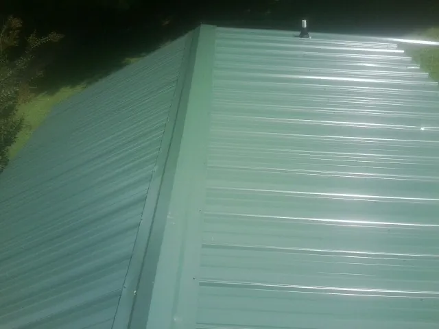New green metal panels meeting at the ridge of a roof — Flat Roof Repair work by our crew in Donalsonville