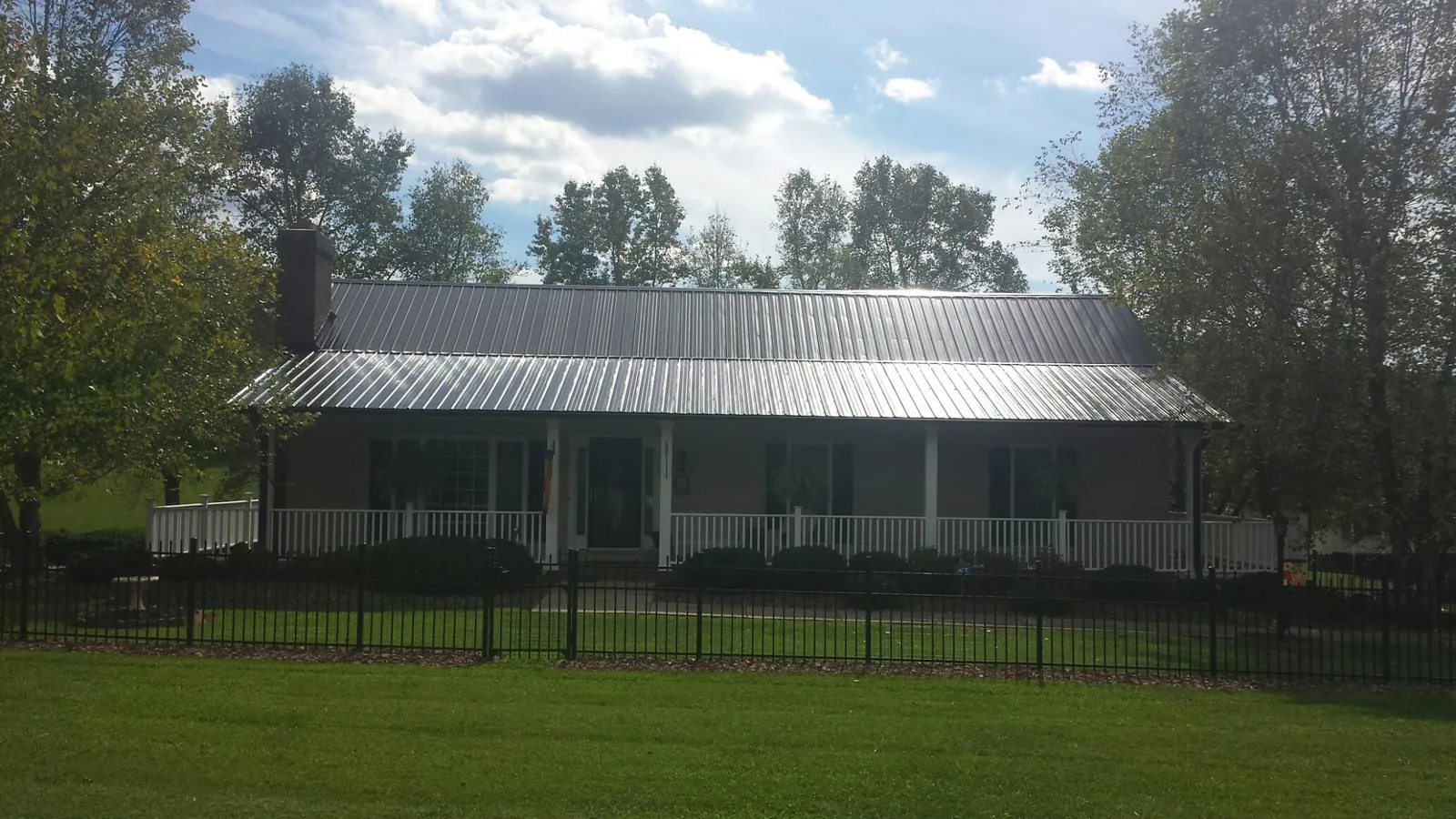 Gray metal roof on a brick ranch with a full width front porch — Gutter Guard Installation work by our crew in Donalsonville
