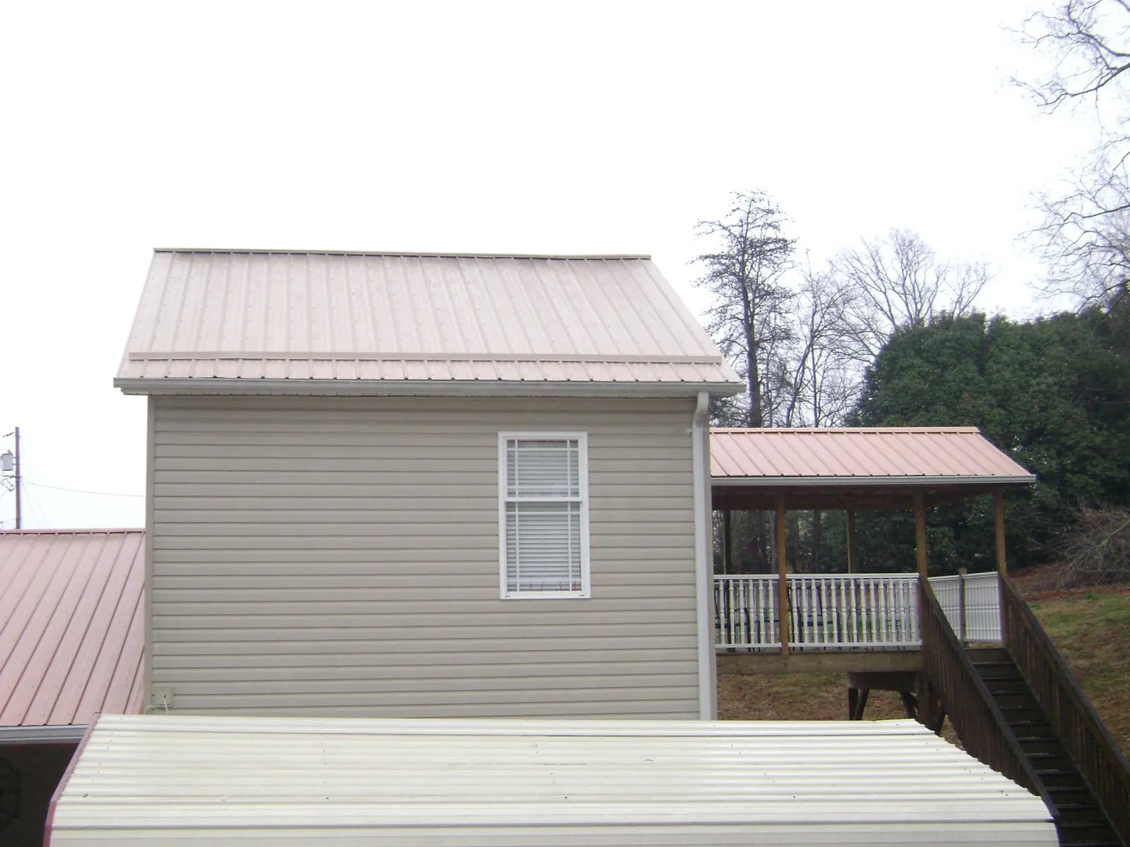 Tan metal roofs on a two story addition and attached porch, from a Roof Replacement job in Donalsonville